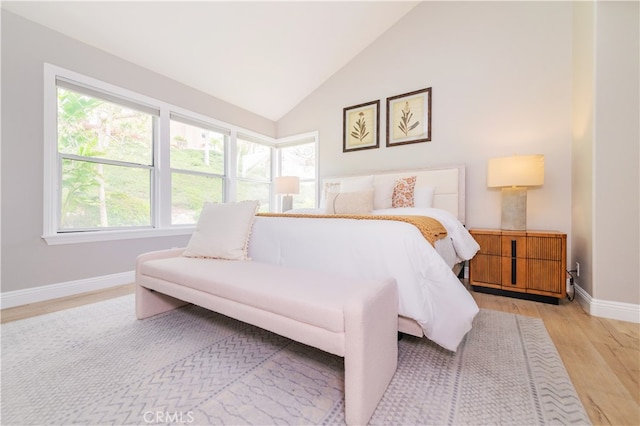 bedroom featuring baseboards, lofted ceiling, and light wood finished floors
