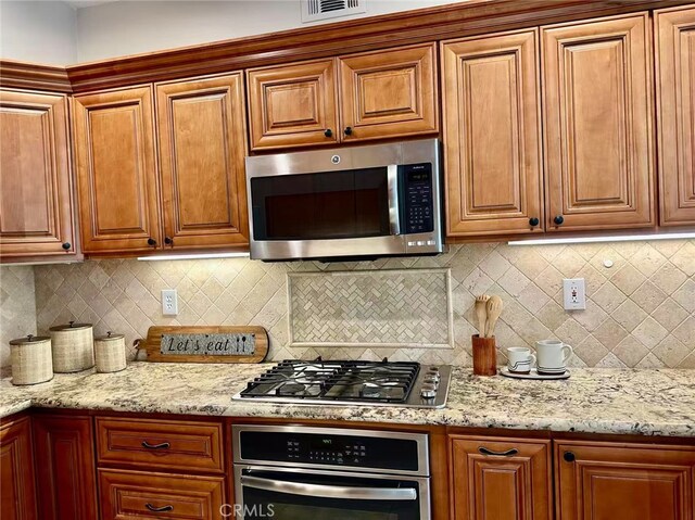 56 Egret Ln, Aliso Viejo, CA 92656 - kitchen featuring stainless steel appliances, tasteful backsplash, light stone countertops, and brown cabinets