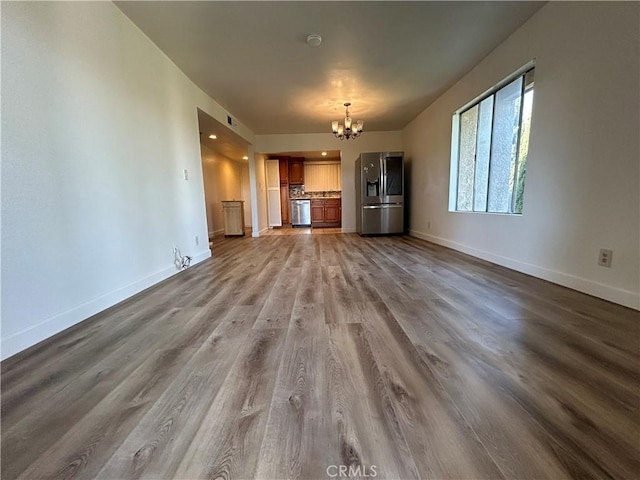 12121 Centralia St Unit 305, Lakewood, CA 90715 - unfurnished living room with baseboards, an inviting chandelier, and wood finished floors