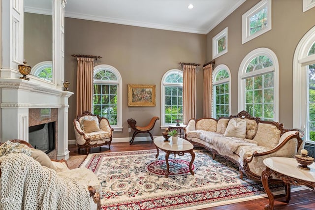living area with a high end fireplace, wood finished floors, baseboards, ornamental molding, and recessed lighting