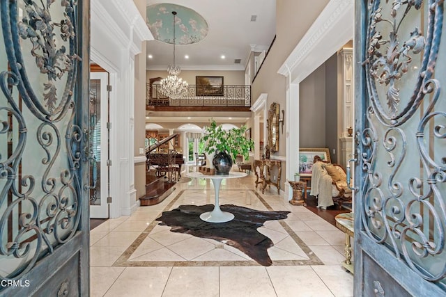 foyer featuring crown molding, a high ceiling, an inviting chandelier, recessed lighting, and visible vents