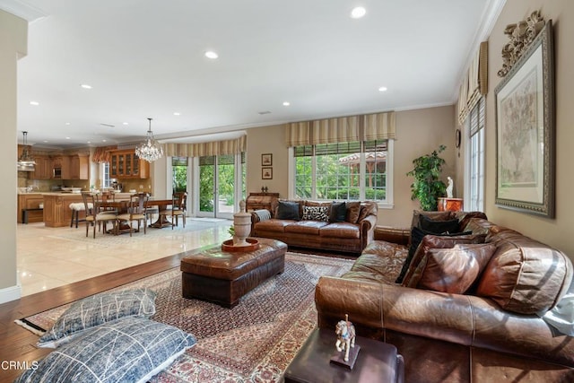 living room with recessed lighting, ornamental molding, a notable chandelier, and light wood-type flooring