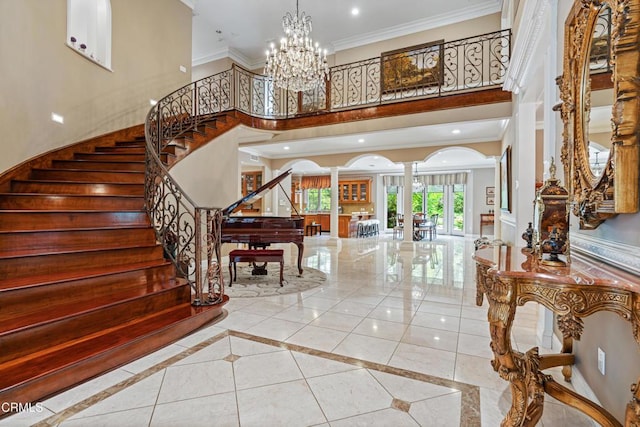 entrance foyer featuring a towering ceiling, stairs, ornate columns, ornamental molding, and recessed lighting