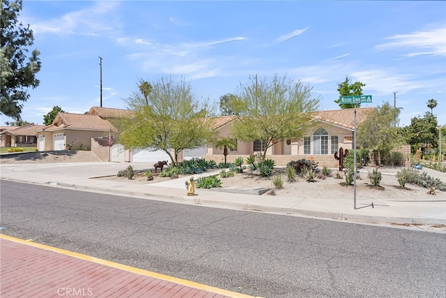 view of front of house featuring concrete driveway, an attached garage, a tile roof, and stucco siding