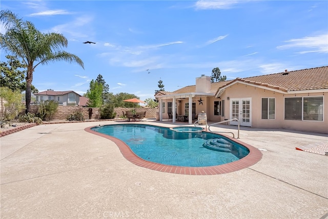 view of pool with a fenced backyard, a patio area, a pool with connected hot tub, and french doors