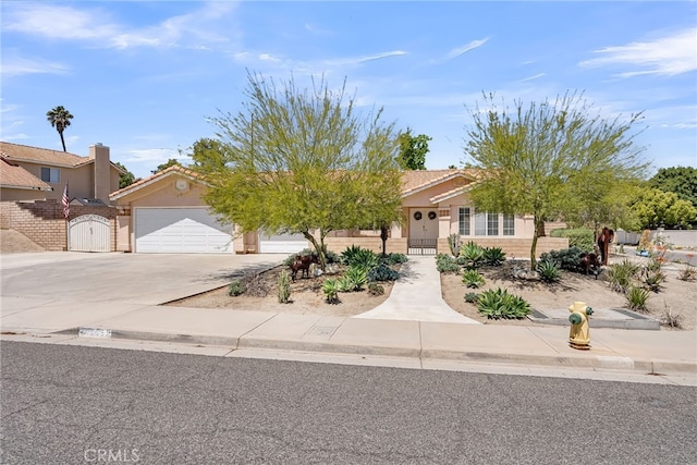 obstructed view of property with a garage, a gate, stucco siding, and driveway