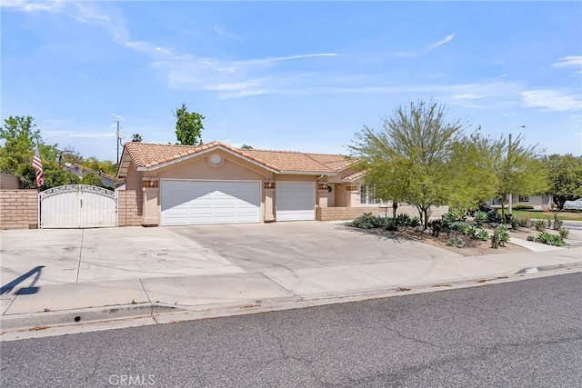 ranch-style home featuring an attached garage, stucco siding, a gate, a tiled roof, and driveway