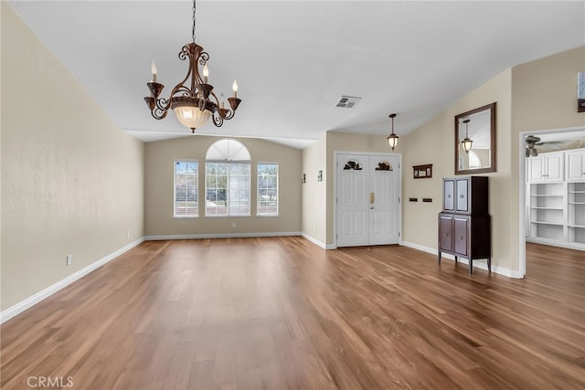 foyer featuring visible vents, a chandelier, wood finished floors, and lofted ceiling