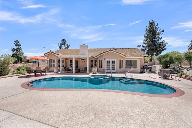 view of pool with a patio area, fence, french doors, and a pool with connected hot tub