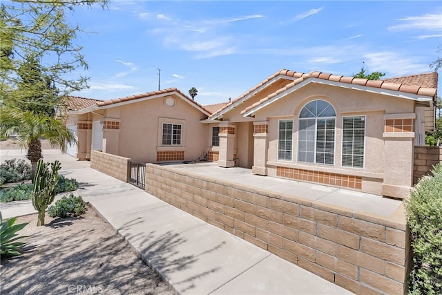 single story home with a fenced front yard, stucco siding, and a tile roof