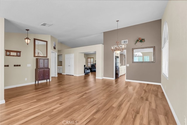 unfurnished living room featuring a notable chandelier, visible vents, baseboards, and light wood finished floors