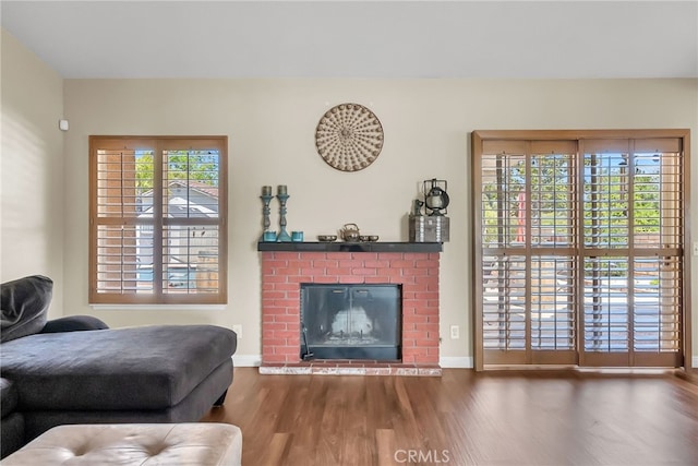 living area with baseboards, a fireplace, and wood finished floors