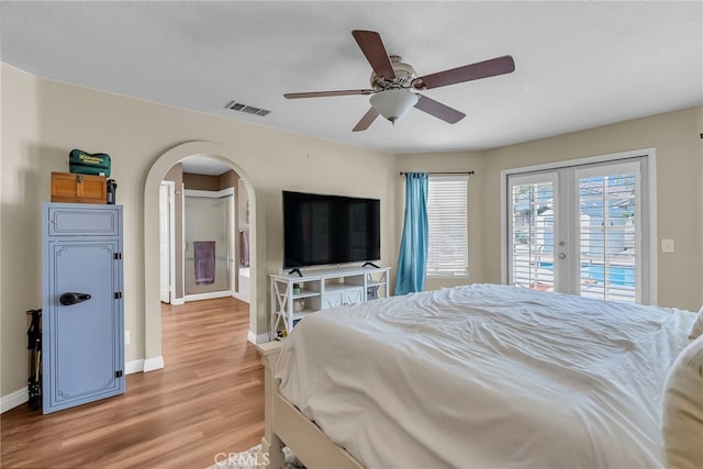 bedroom featuring visible vents, arched walkways, baseboards, light wood-style floors, and access to outside