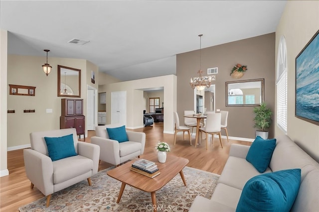 living area featuring an inviting chandelier, a wealth of natural light, light wood-type flooring, and visible vents