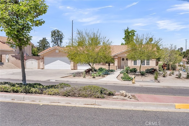 obstructed view of property with driveway, a gate, a tile roof, and stucco siding