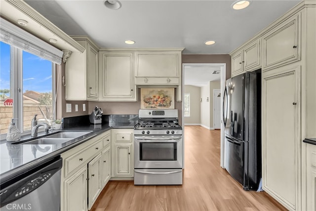 kitchen featuring light wood-style floors, appliances with stainless steel finishes, cream cabinets, and a sink