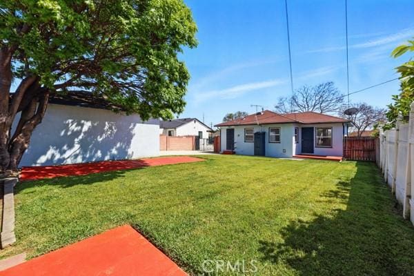 325 W Floral Dr, Monterey Park, CA 91754 - back of house with a fenced backyard, a patio, stucco siding, and a lawn