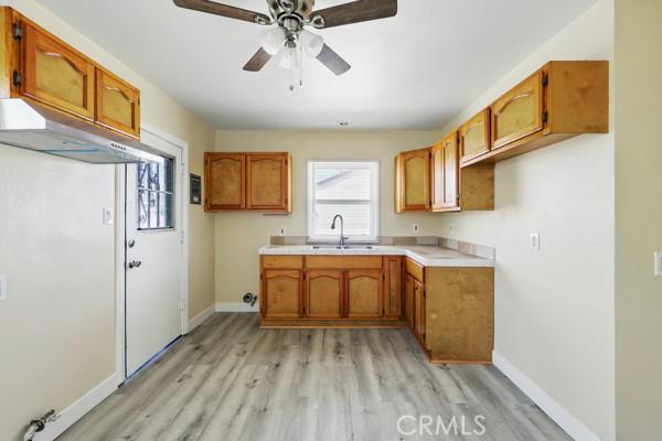 325 W Floral Dr, Monterey Park, CA 91754 - kitchen featuring ceiling fan, brown cabinetry, light countertops, a sink, and light wood-style floors