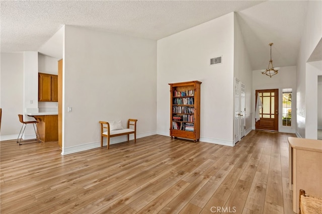429 Indian Wells Rd, Banning, CA 92220 - foyer entrance with light wood finished floors, a chandelier, high vaulted ceiling, baseboards, and a textured ceiling