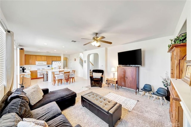 living area featuring arched walkways, ceiling fan, recessed lighting, and visible vents