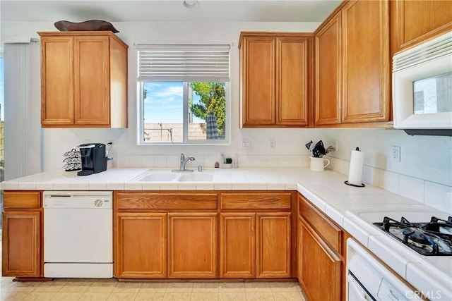 kitchen with brown cabinetry, a sink, and white appliances