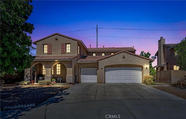 mediterranean / spanish-style house with covered porch, driveway, a tile roof, an attached garage, and stucco siding