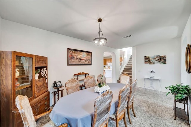 dining area with stairway, arched walkways, carpet, and visible vents