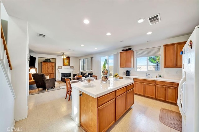 kitchen featuring a fireplace, white refrigerator with ice dispenser, tile countertops, and visible vents