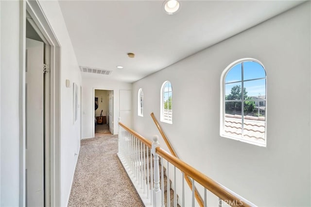 hallway with plenty of natural light, carpet, visible vents, and an upstairs landing