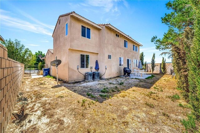 back of house featuring a fenced backyard, a patio area, stucco siding, and central AC unit
