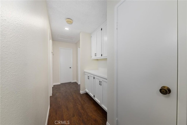 hallway featuring dark wood-type flooring and baseboards