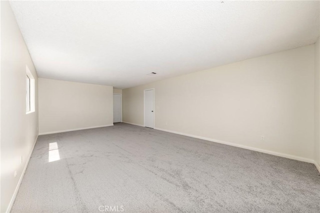 carpeted spare room featuring baseboards