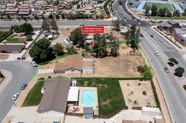 aerial perspective of suburban area featuring a pool, property boundaries highlighted, and a major roadway