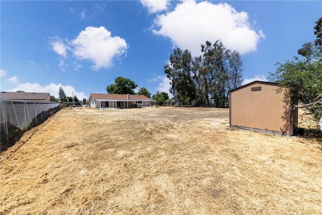 view of yard with fence, a shed, and an outdoor structure