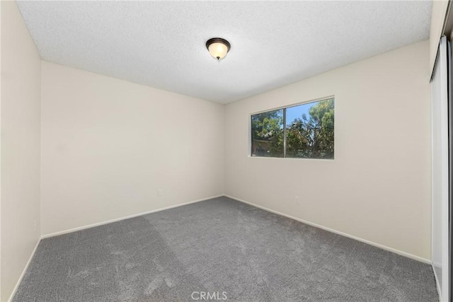 unfurnished room featuring carpet floors, baseboards, and a textured ceiling