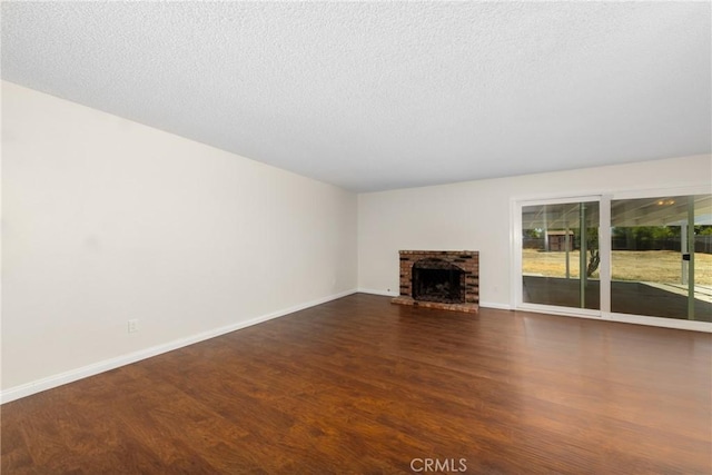 unfurnished living room with wood finished floors, baseboards, a fireplace, and a textured ceiling