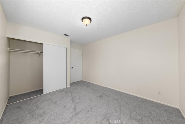unfurnished bedroom with carpet flooring, a closet, a textured ceiling, and baseboards