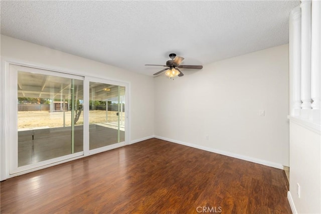 spare room with wood finished floors, ornate columns, a ceiling fan, baseboards, and a textured ceiling