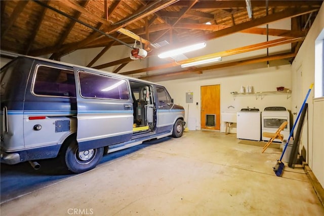 garage with washer and clothes dryer, a garage door opener, and electric panel