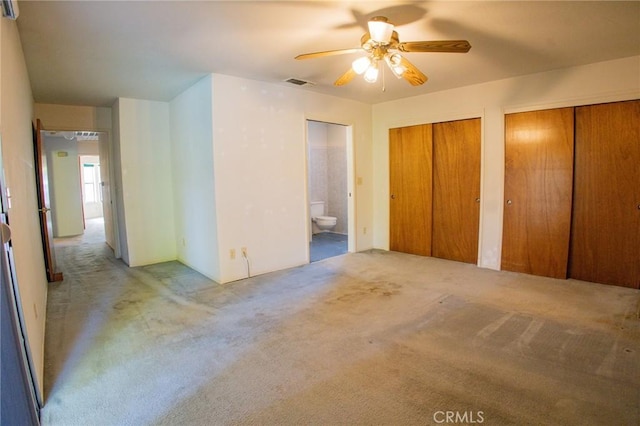 unfurnished bedroom with ceiling fan, ensuite bath, carpet floors, multiple closets, and visible vents