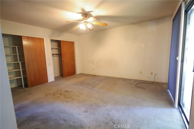 unfurnished bedroom with ceiling fan, multiple closets, and carpet