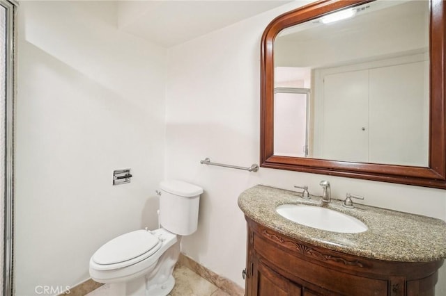 bathroom featuring tile patterned flooring, vanity, baseboards, toilet, and a shower with door