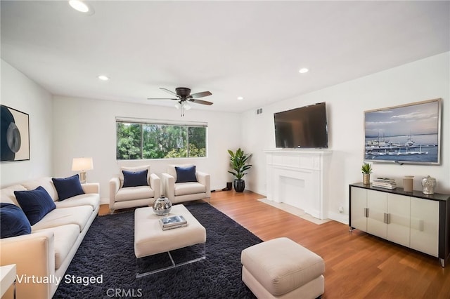 living area with visible vents, light wood-style floors, ceiling fan, recessed lighting, and a fireplace with flush hearth