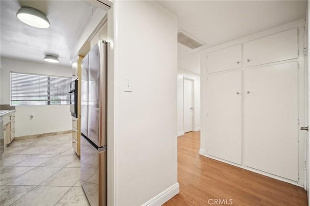 corridor with visible vents, light wood-style flooring, and baseboards