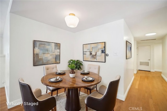 dining room featuring light wood-type flooring, baseboards, and visible vents