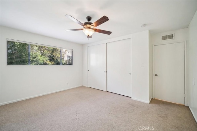 unfurnished bedroom with ceiling fan, light colored carpet, baseboards, visible vents, and a closet