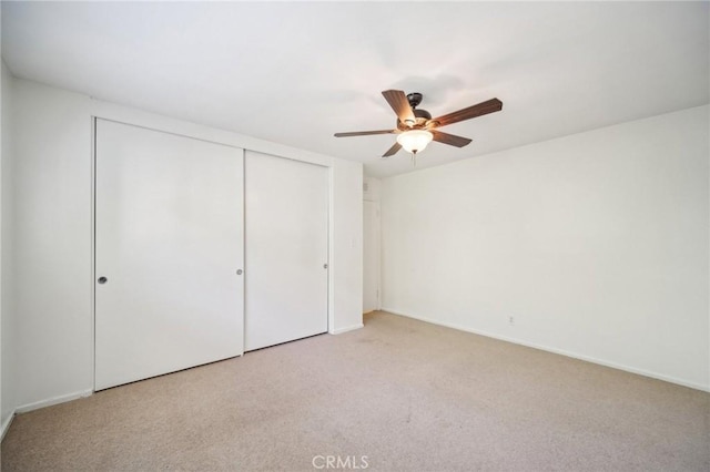 unfurnished bedroom featuring a closet, carpet flooring, baseboards, and a ceiling fan