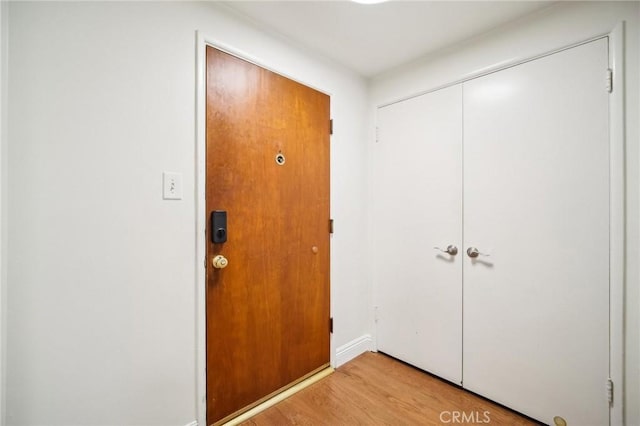 doorway featuring baseboards and light wood finished floors