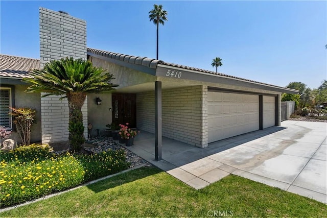 5410 Via, San Jacinto, Riverside, CA 92506 - view of front facade featuring a chimney, a garage, brick siding, stucco siding, and a tiled roof