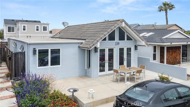 rear view of house with a patio, fence, french doors, and stucco siding